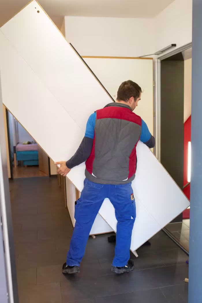 Möbelpacker transportiert Platte über Treppe