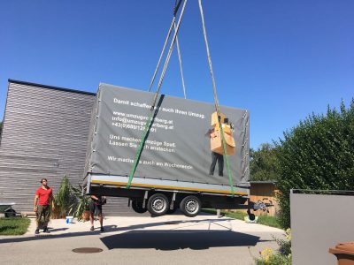 Umzugsanhänger wird mit Kran verladen