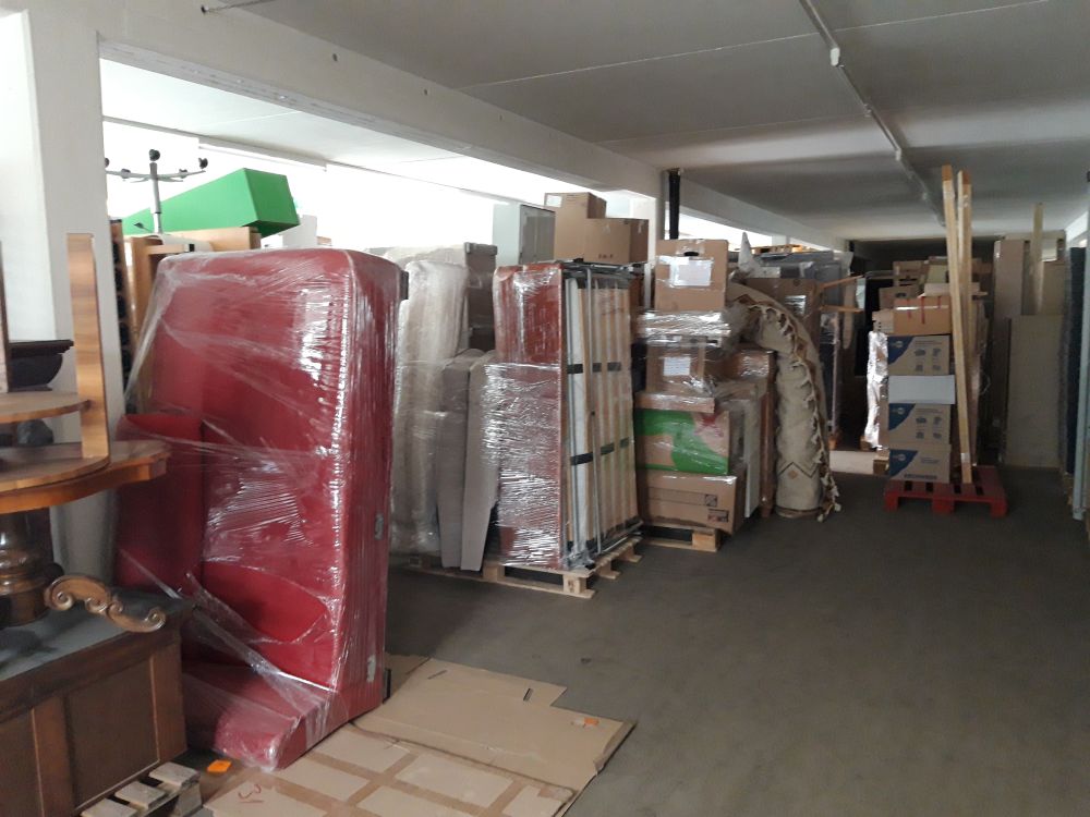 Lagerraum mit sorgfältig verpackten Möbeln, Kartons und Umzugsgut, ordentlich auf Paletten gestapelt.