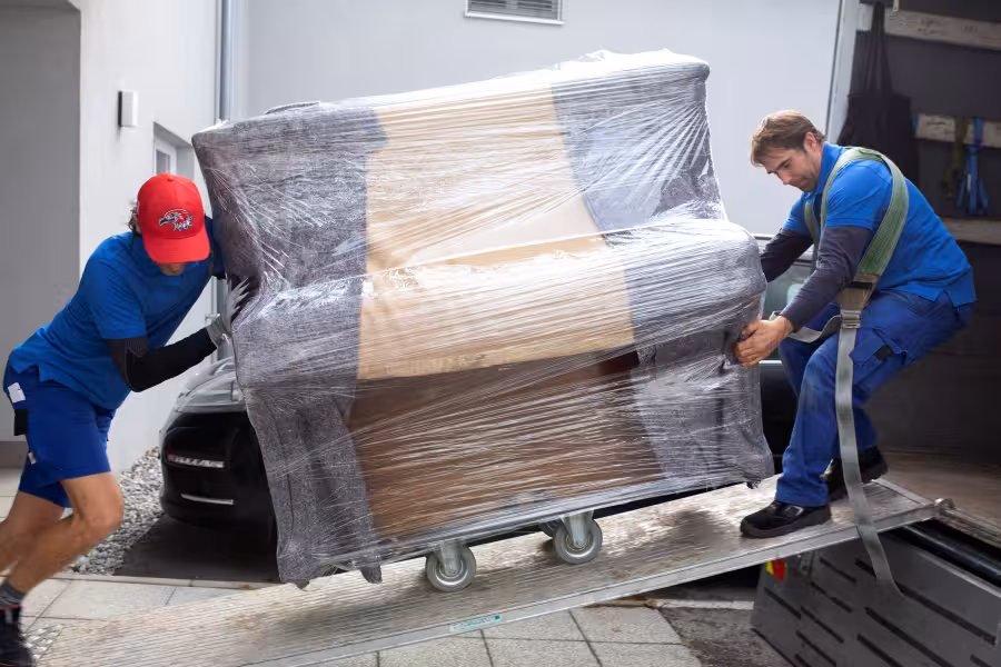 Umzugshelfer transportieren Klavier auf Rollwagen